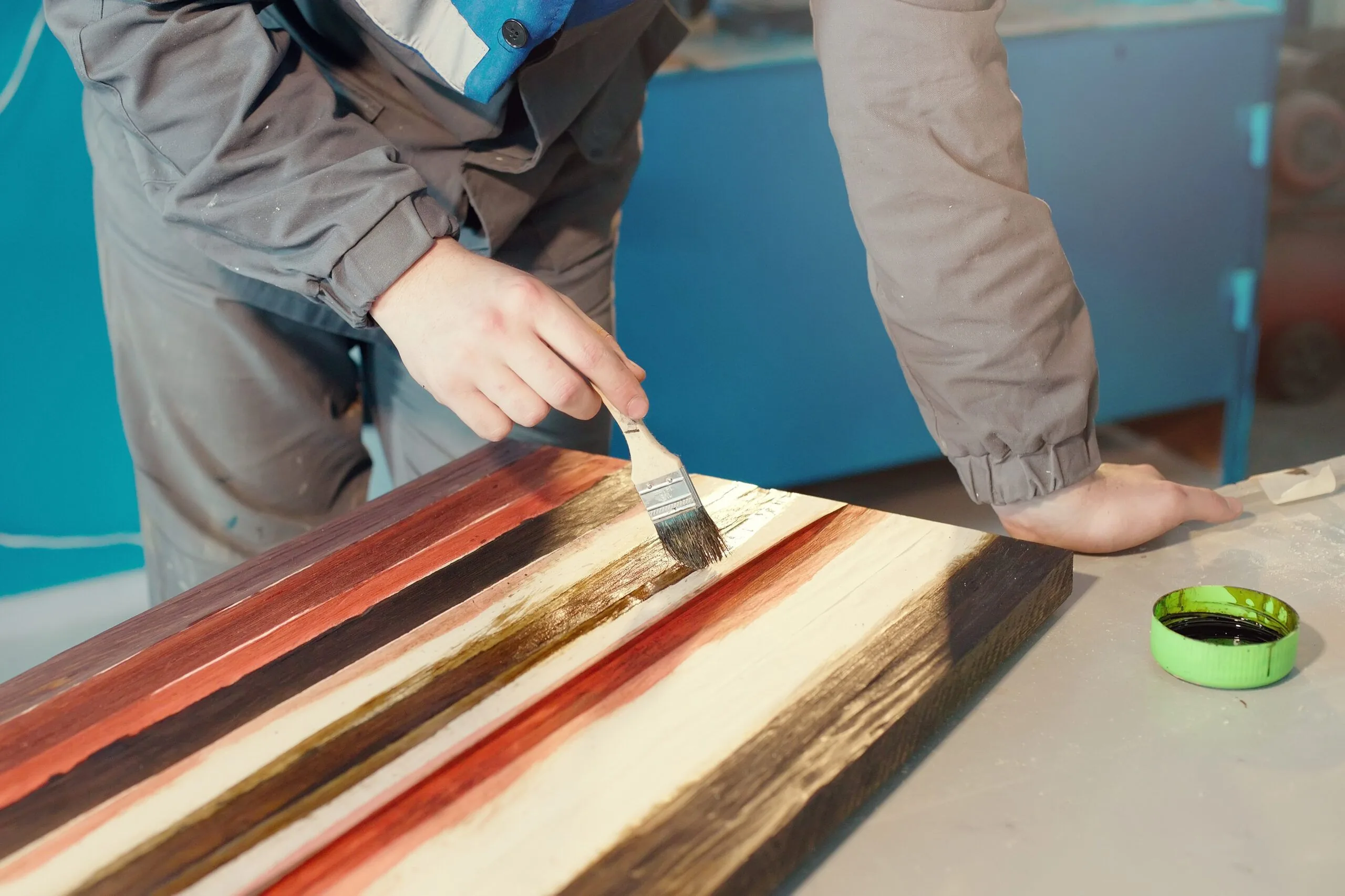 Working cabinetmaker holds brush his hand paints wooden surface