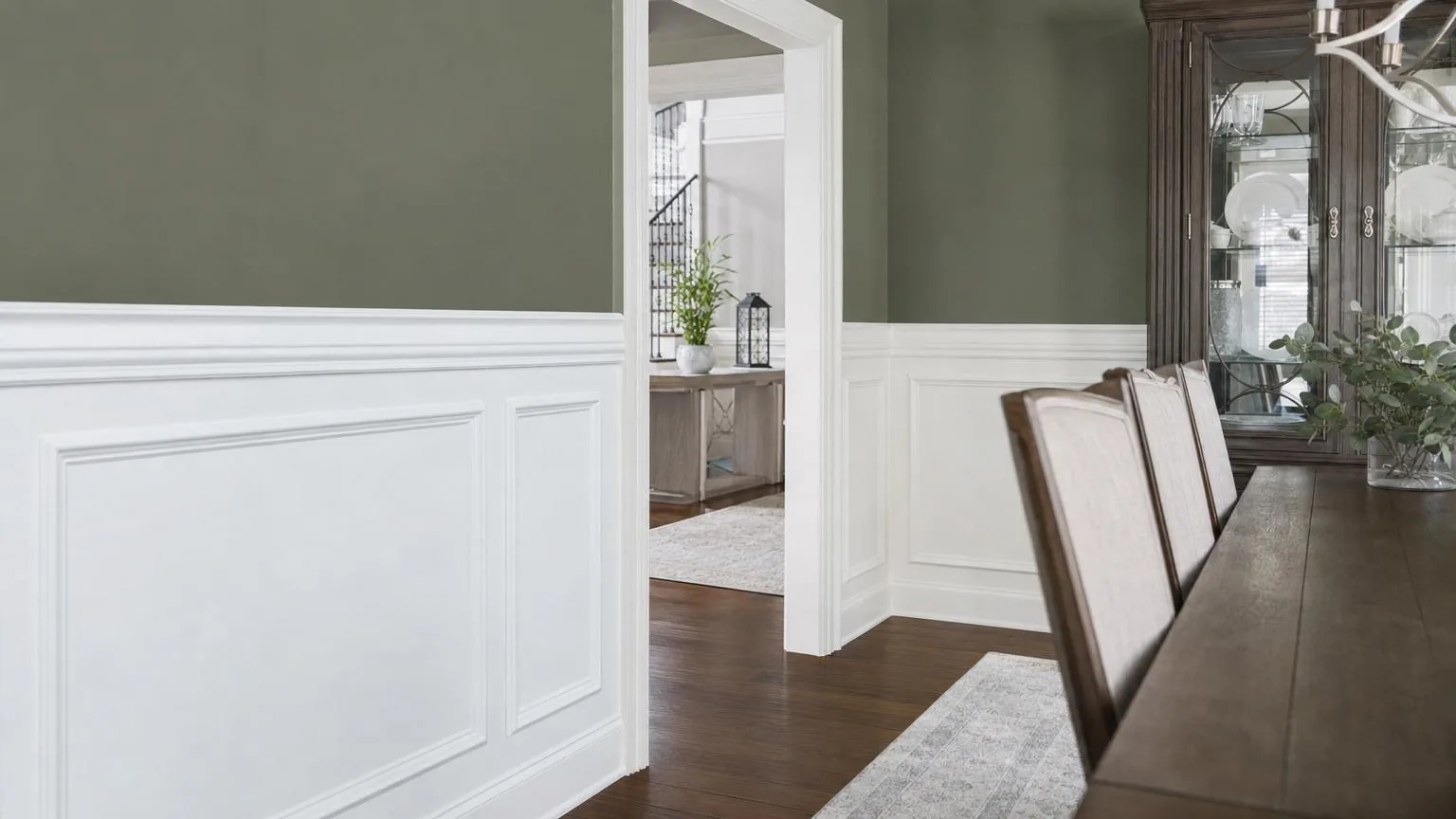 Dining room with white painted wainscoting paneling below sage green walls