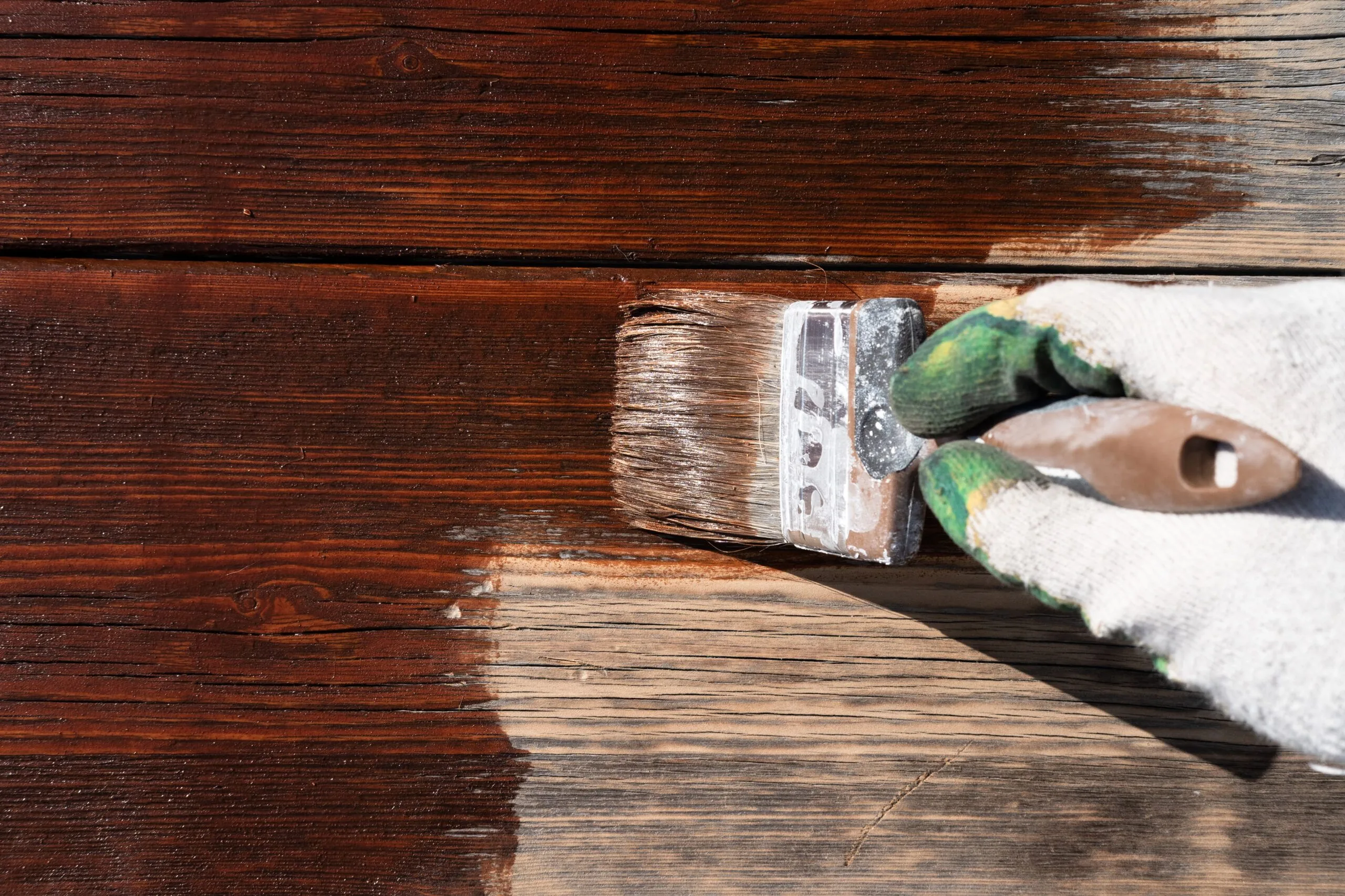 Brush applying stain to a freshly finished wooden table